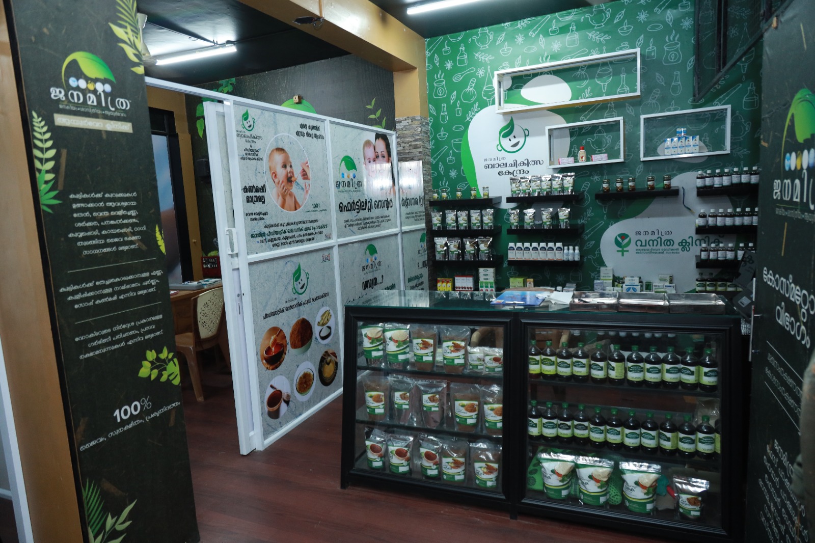 Inside the Janamitra Ayurveda Centre: the pharmacy counter and display cabinets, with the Bala Chikitsa Kendram and Vanitha Clinic areas beyond